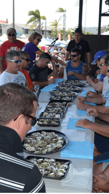 Men sit around a table eating as many oysters as they can.