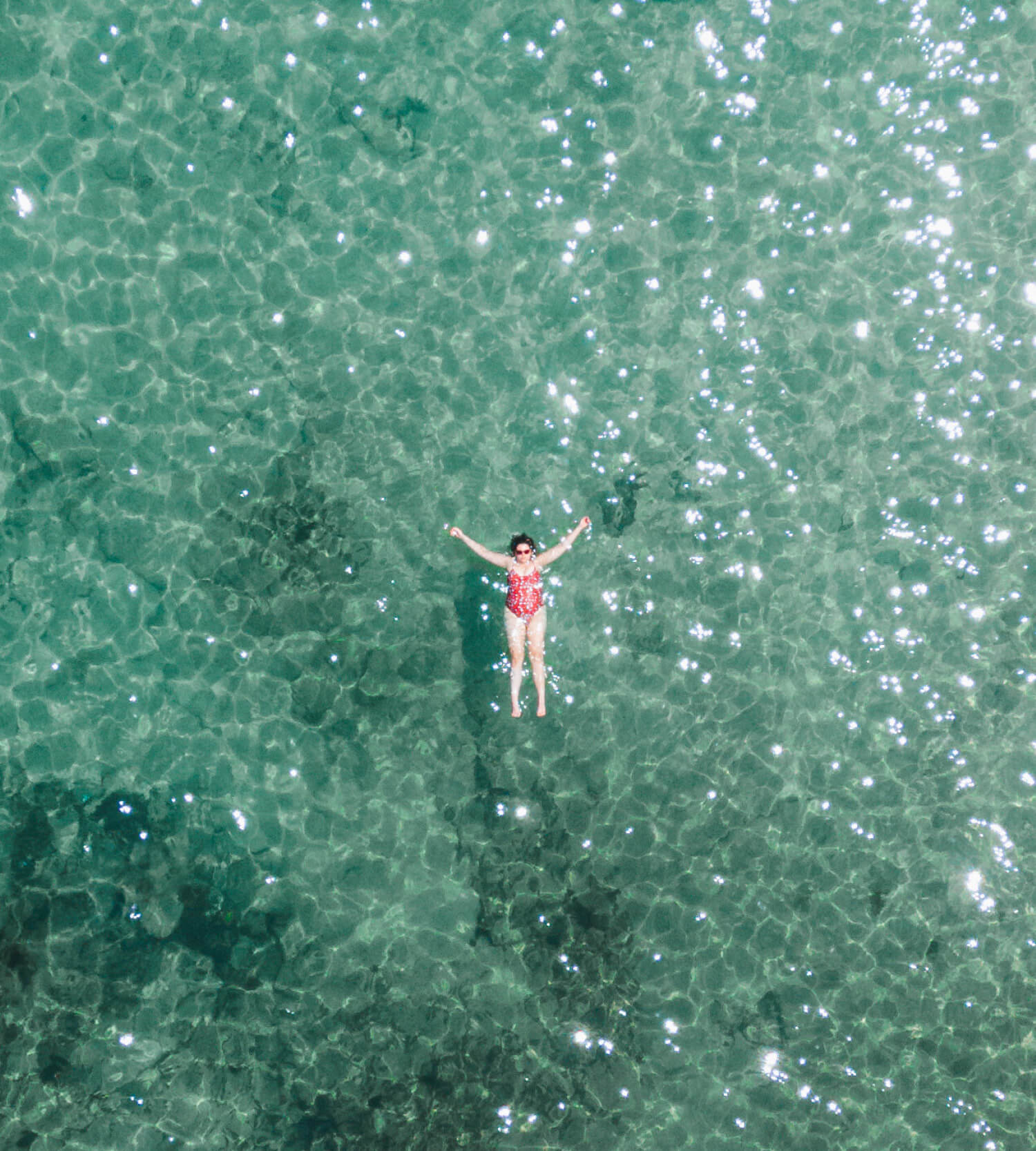 Birds eye view of lady floating on her back in turquoise water