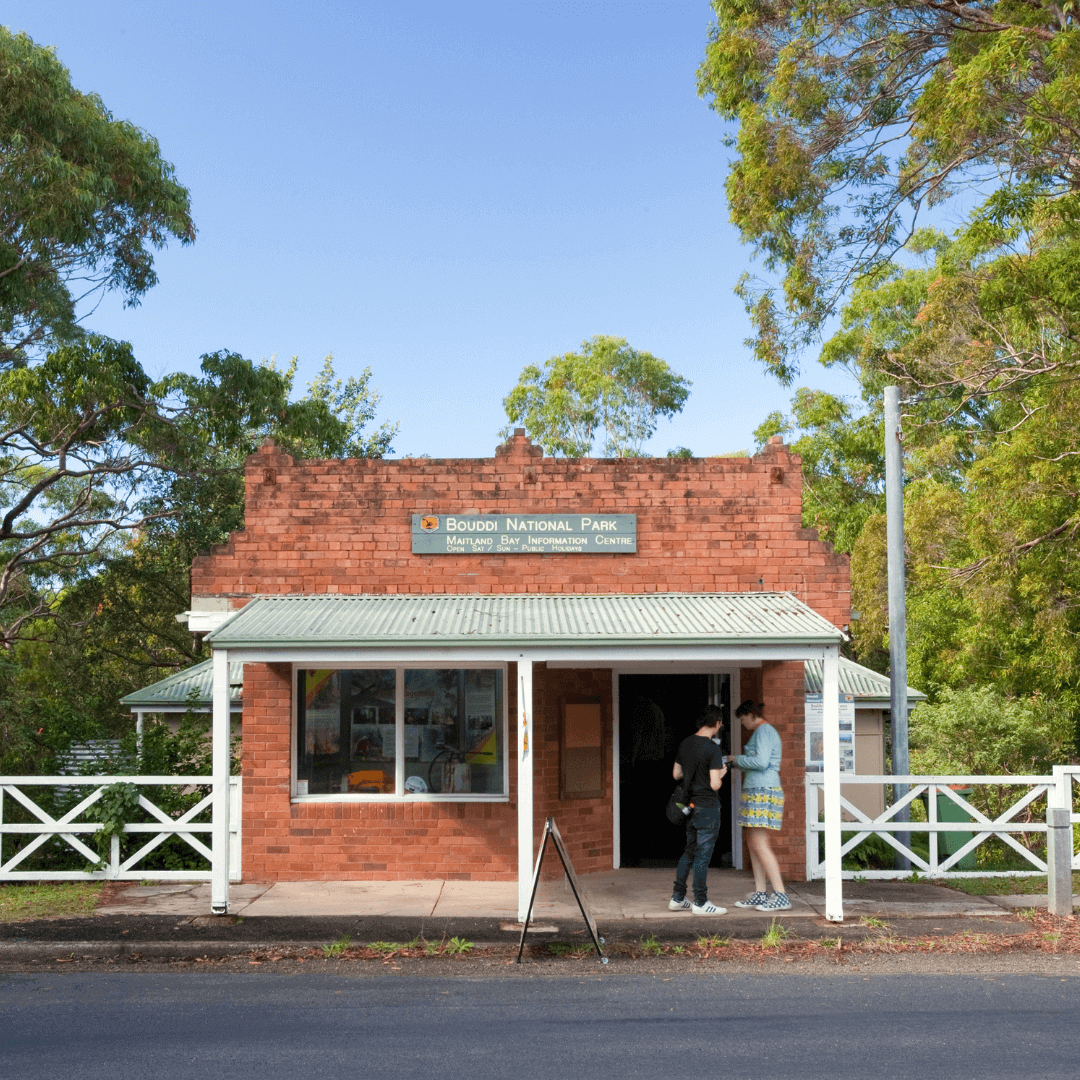 A small terracotta brick building with two people entering.