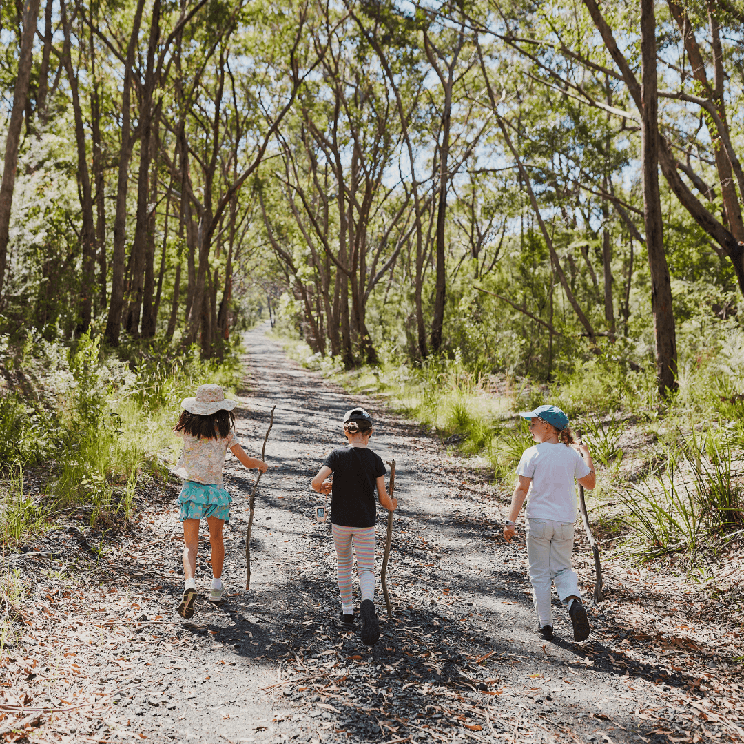 Three girls walking along a path throughout bushland