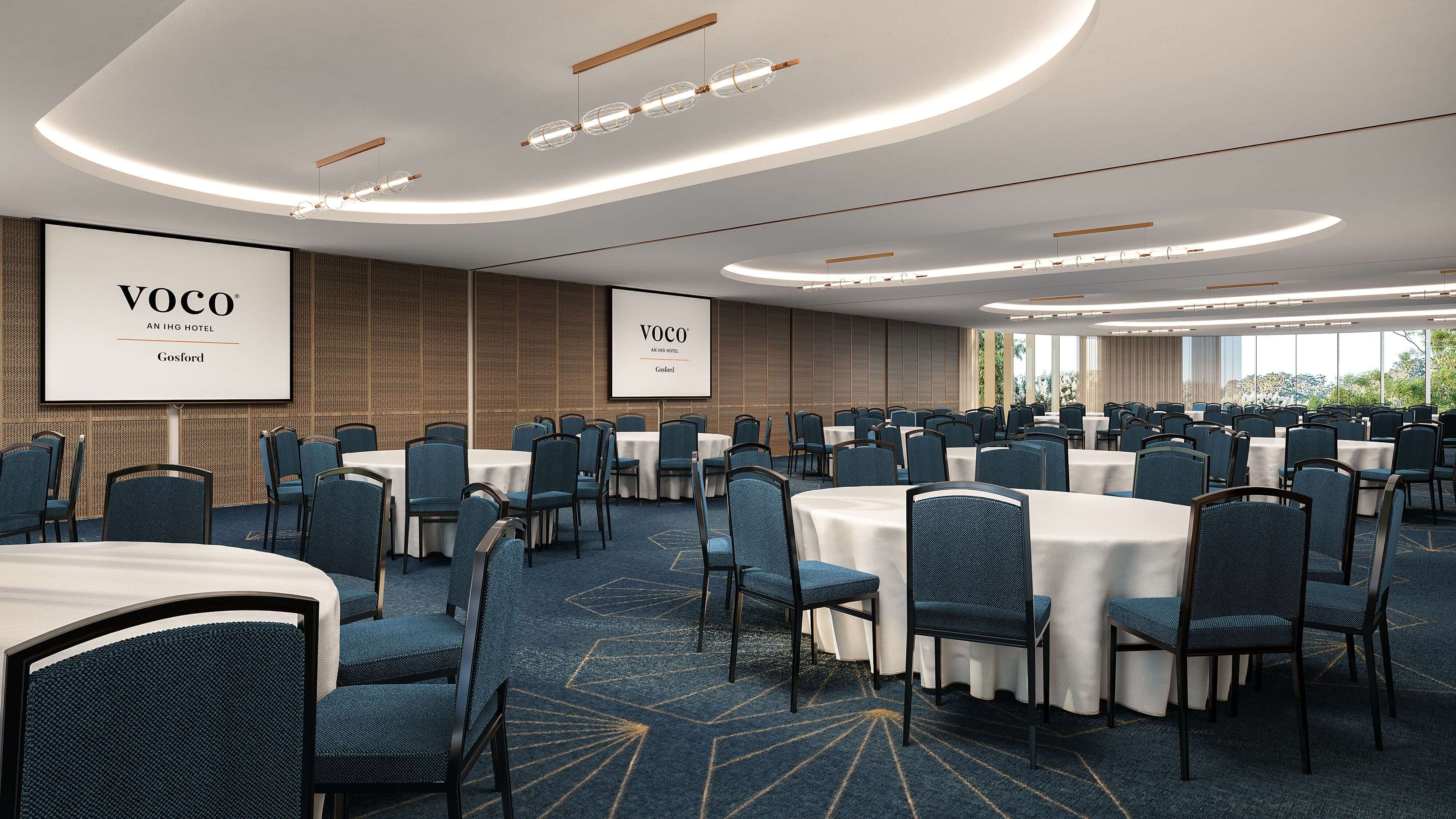 A function room with round tables, dark navy setting and three display screens promoting Voco Gosford