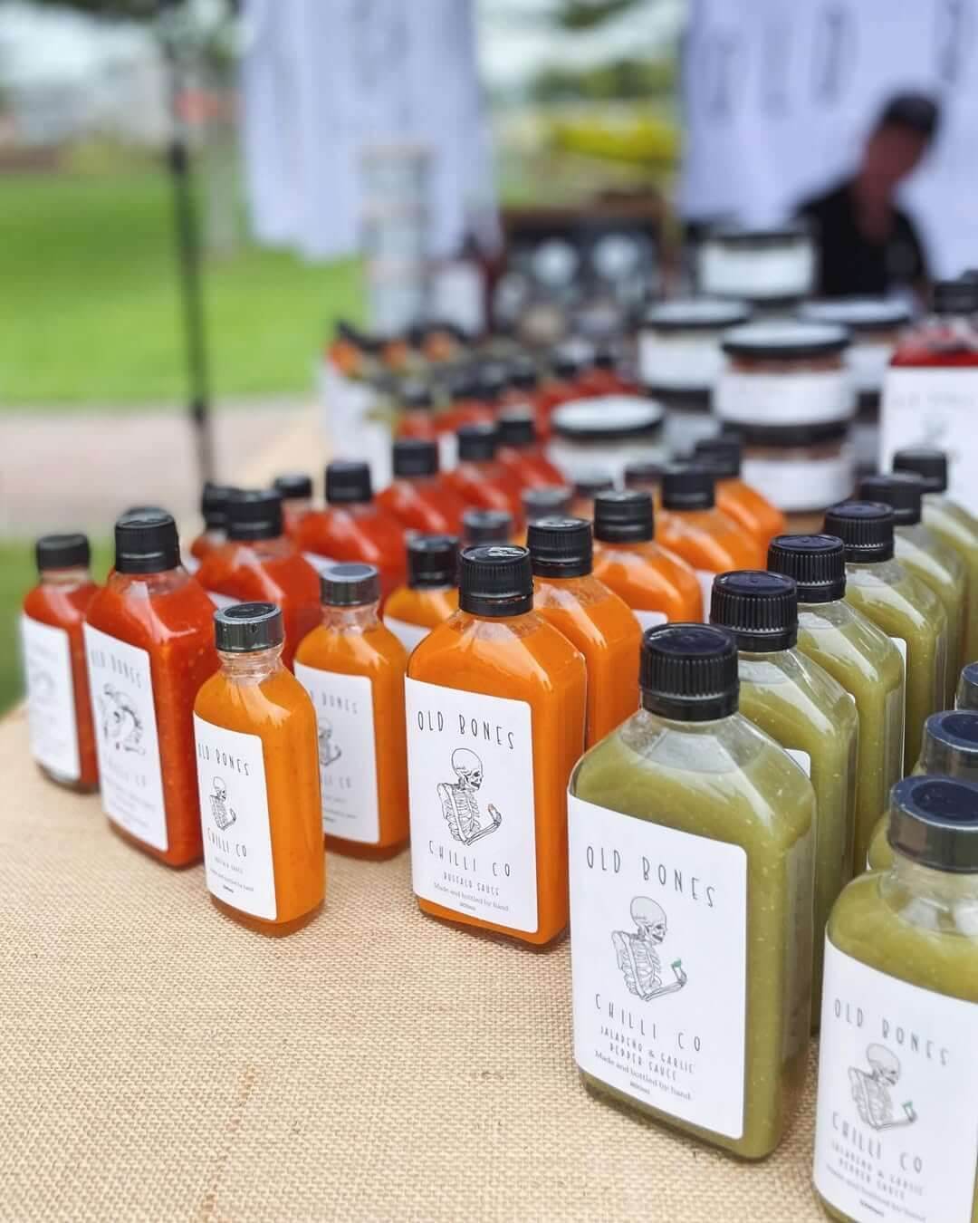 A collection of orange, red and green coloured chilli sauces in glass bottles