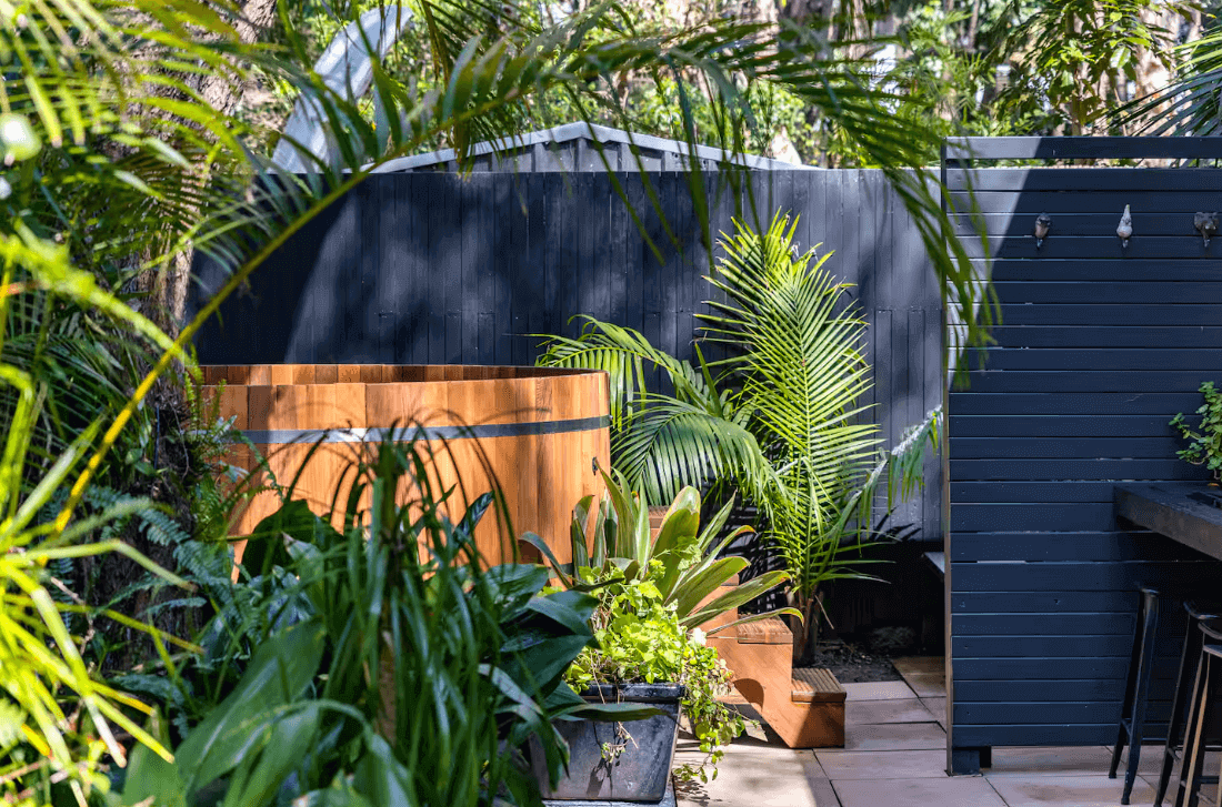 An outdoor hottub surrounded by tropical plants in a backyard