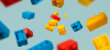 Red, blue, and yellow Lego float on a light blue background