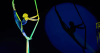 Duo AussieBela performing a dramatic aerial balance against a dark stage background, showcasing their cirque-style artistry