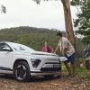 two people leaning on an ev charging car